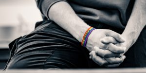 Foto einer Person, die ein Regenbogen-Armband mit der Aufschrift 100% Mensch trägt